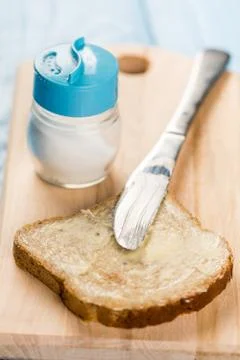 Flat lay butter spread on bread with knife and saltshaker served on a wooden  Stock Photos