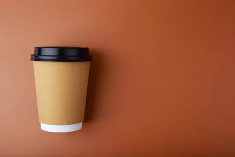 Flat lay with cardboard cup of coffee on brown background with copy space Stock Photos