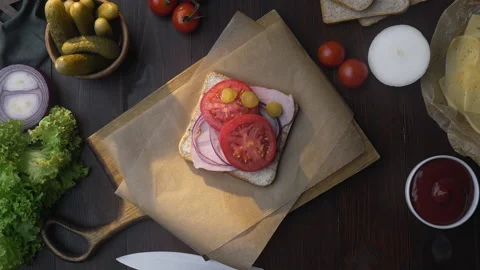 Flat lay of chefs hand adds sliced tomatoes to the sandwich Stock Footage 143783533