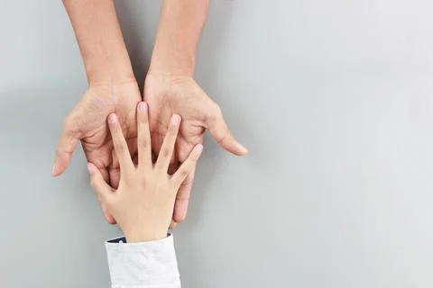 Flat lay child small hand put on father hands-on gray background with love an Stock Photos