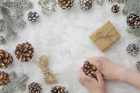 Flat lay children's hands hold cone, craft handmade gift box, rope, fir branches Stock Photos