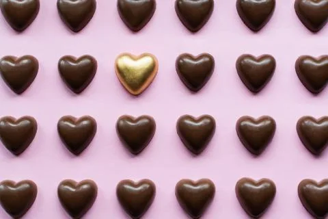 Flat lay with chocolate hearts featuring one golden candy standing out Stock Photos