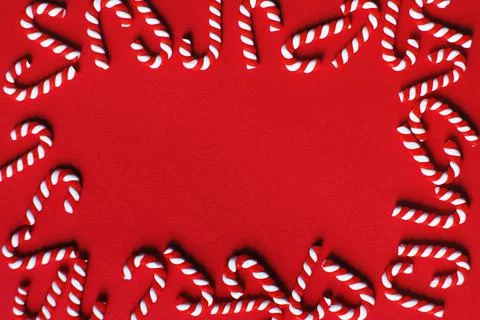 Flat lay Christmas composition with frame of candy canes on a red background. 스톡 사진