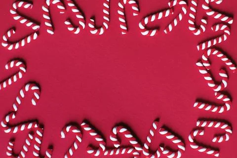 Flat lay Christmas composition with frame of candy canes on a red background. Stock Photos