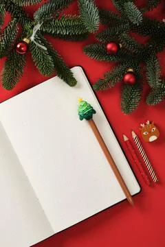 Flat Lay Christmas notes with open notepad and holiday pencils on a red bac.. Stock Photos
