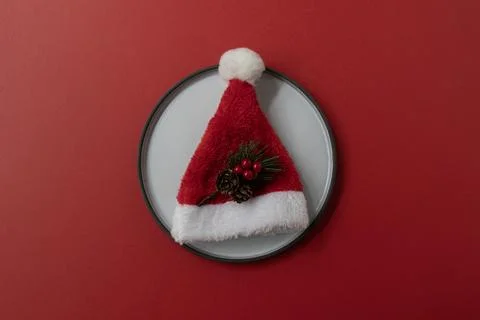 Flat Lay Christmas Table Setting with Santa Hat on Plate Against Red Backgrou Stock Photos