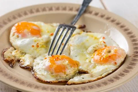 Flat lay closeup macro fried chicken eggs on the plate above wooden table Stock Photos