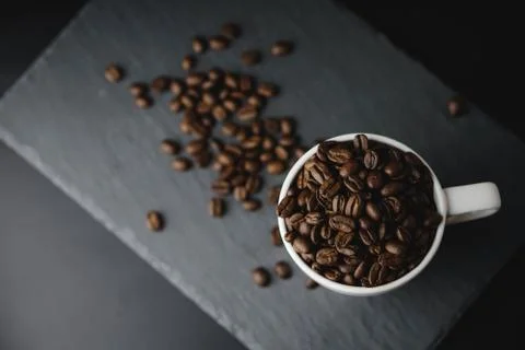Flat lay of Coffee bean on white cup over a stone rock slate background. Cele Stock Photos