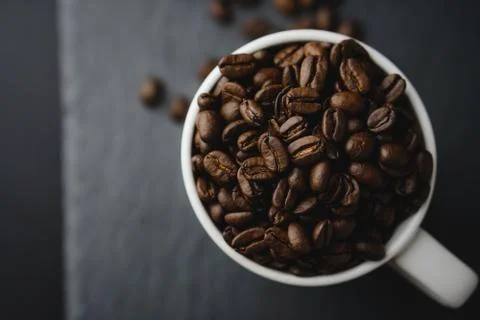 Flat lay of Coffee bean on white cup over a stone rock slate background. Cele Foto stock