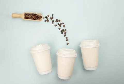 Flat lay of coffee beans pouring into a paper cup, blue backdrop used for f.. Foto stock