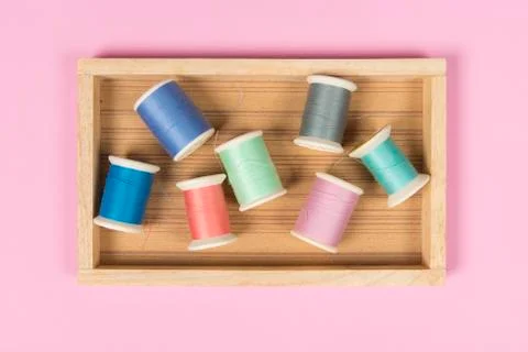 Flat lay of colored thread rolls for sewing on pink background, Sewing and ne Stock Photos