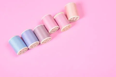 Flat lay of colored thread rolls for sewing on pink background, Sewing and ne Stock Photos
