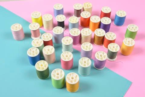 Flat lay of colored thread rolls for sewing on two tone background, Sewing an Stock Photos
