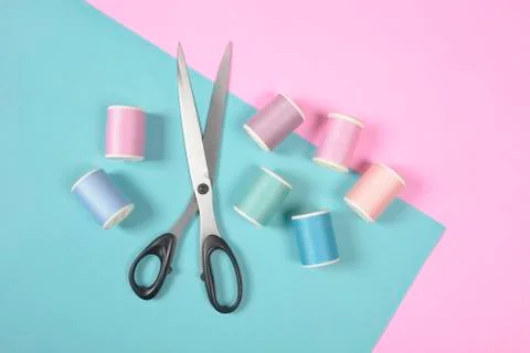 Flat lay of colored thread rolls and Scissors for sewing on two tone backgrou Stock Photos