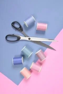 Flat lay of colored thread rolls and Scissors for sewing on two tone backgrou Stock Photos