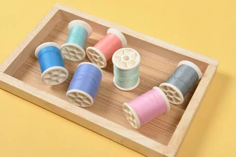 Flat lay of colored thread rolls for sewing on yellow background, Sewing and  Stock Photos