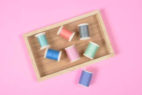 Flat lay of colored thread rolls for sewing on pink background, Sewing and ne Stock Photos