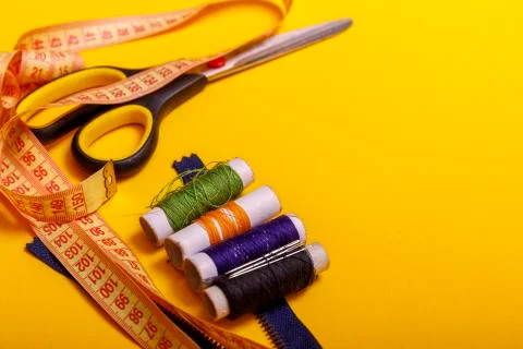 Flat lay of colored thread rolls and Scissors for sewing yellow background. S Stock Photos