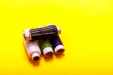 Flat lay of colored thread rolls and Scissors for sewing yellow background. S Stock Photos