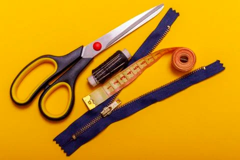 Flat lay of colored thread rolls and Scissors for sewing yellow background. S Stock Photos
