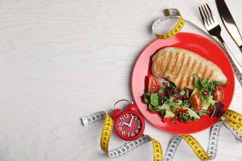 Flat lay composition with appetizing food and alarm clock on white wooden tab Foto stock
