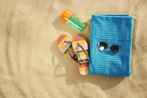 Flat lay composition of beach objects and towel on sand, space for text Stock-Fotos