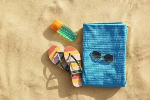 Flat lay composition of beach objects and towel on sand, space for text Stock Photos