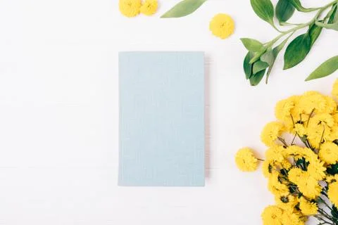 Flat lay composition of blue notepad next to yellow bouquet Stock Photos
