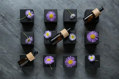 Flat lay composition with bottles of essential oil and beautiful flowers on d Stock Photos