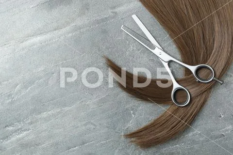 Photo Hairdresser's scissors with comb and strand of blonde hair on grey  background