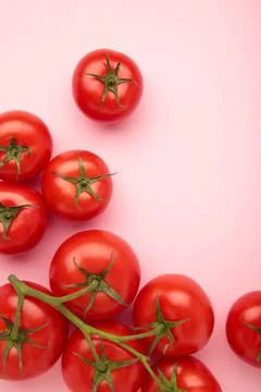 Flat lay composition with bunch of tomatoes on pink background. Vertical phot Stock Photos