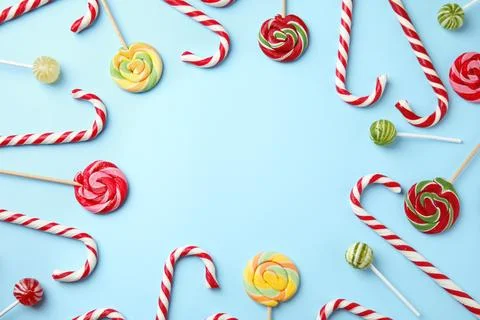 Flat lay composition with candy canes and lollipops on light blue background. Stock Photos