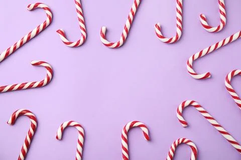 Flat lay composition with candy canes on lilac background. Space for text Stock Photos