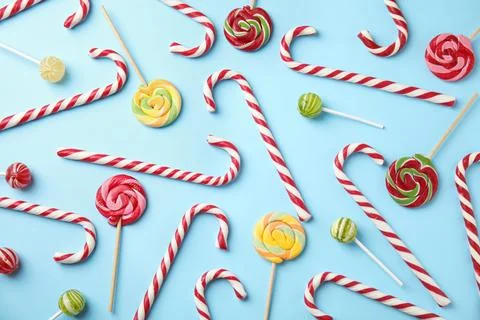 Flat lay composition with candy canes and lollipops on light blue background Stock Photos