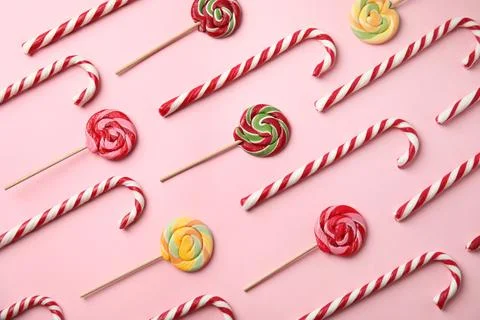 Flat lay composition with candy canes and lollipops on pink background Stock Photos