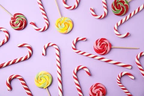Flat lay composition with candy canes and lollipops on lilac background Stock Photos