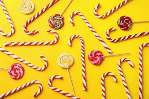 Flat lay composition with candy canes and lollipops on yellow background Stock Photos