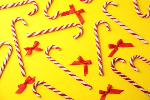 Flat lay composition with candy canes and red bows on yellow background Stock Photos
