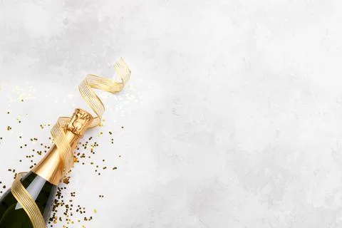 Flat lay composition of Champagne bottle and confetti on grey stone backgroun Stock Photos