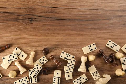 Flat lay composition of chess pieces and dominoes on wooden table, space for  Stockfoto's