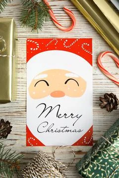 Flat lay composition with Christmas card and gift boxes on white wooden backg Stock Photos