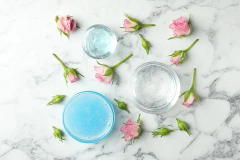 Flat lay composition with cosmetic gel and beautiful flowers on white marble  Foto stock