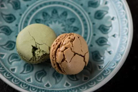 Flat lay composition with cracked macaroons on green plate Stock Photos