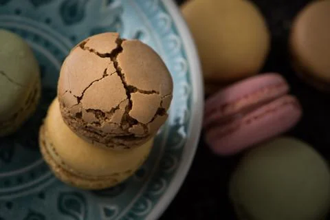 Flat lay composition with cracked macaroons on green plate Foto stock