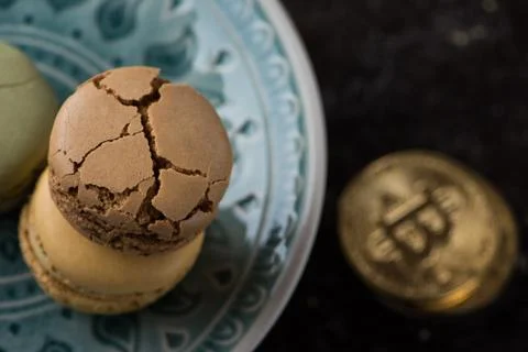 Flat lay composition with cracked macaroons on green plate with bitcoins Stock Photos