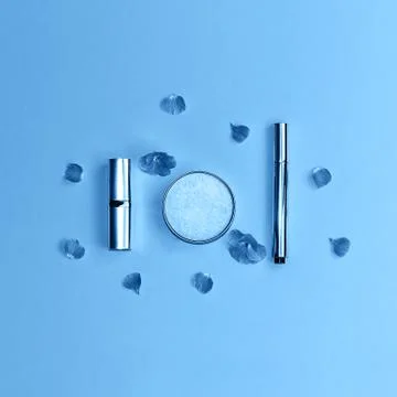 Flat lay composition with decorative makeup products and flowers on trendy blue Stock Photos