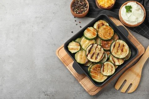 Flat lay composition with delicious grilled zucchini slices on grey table. Sp Stock Photos