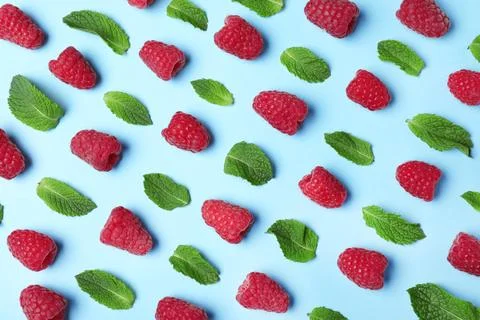 Flat lay composition with delicious ripe raspberries and leaves on blue backg Foto stock