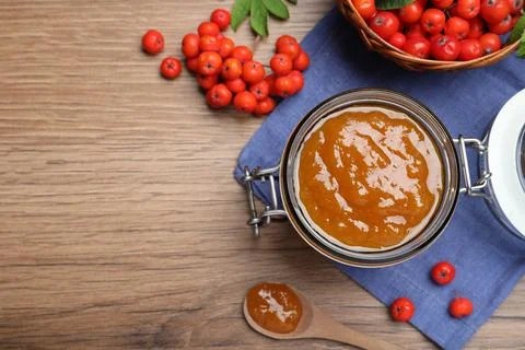 Flat lay composition with delicious rowan jam and berries on wooden table. Sp Stock Photos