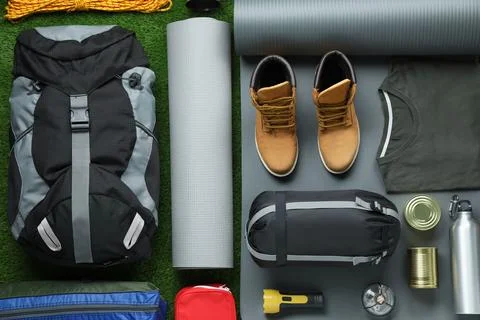 Flat lay composition with different camping equipment on green grass Stock Photos
